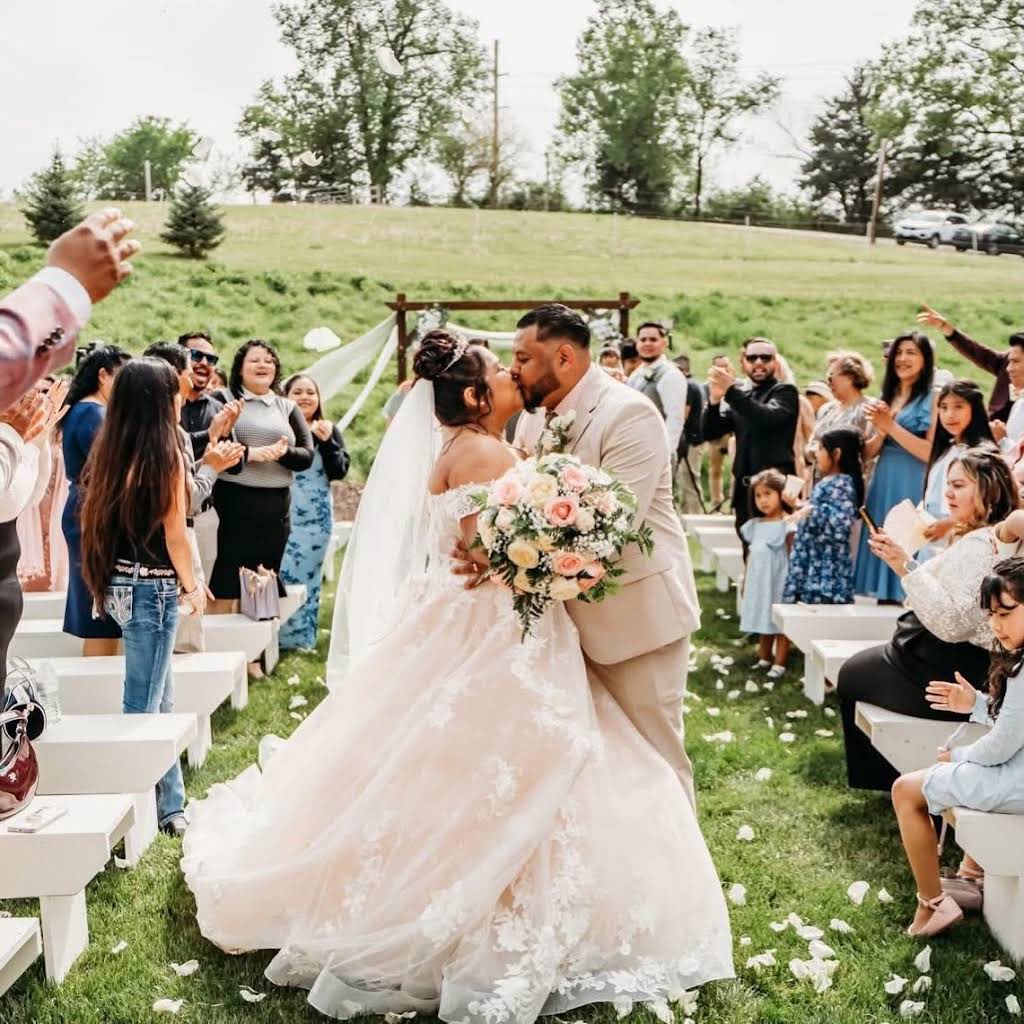 Yanet and her partner walking back down the outdoor ceremony aisle at Bella's