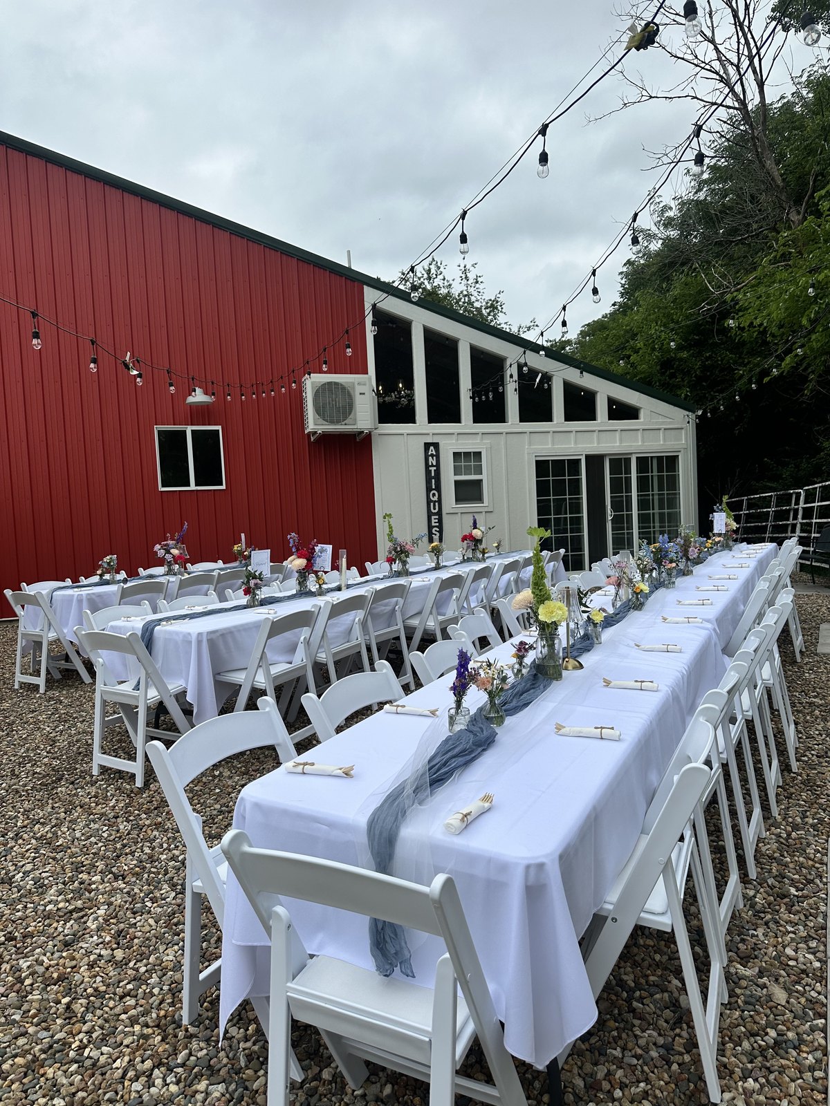 Long reception tables set beside the red barn at Bella's Farmhouse
