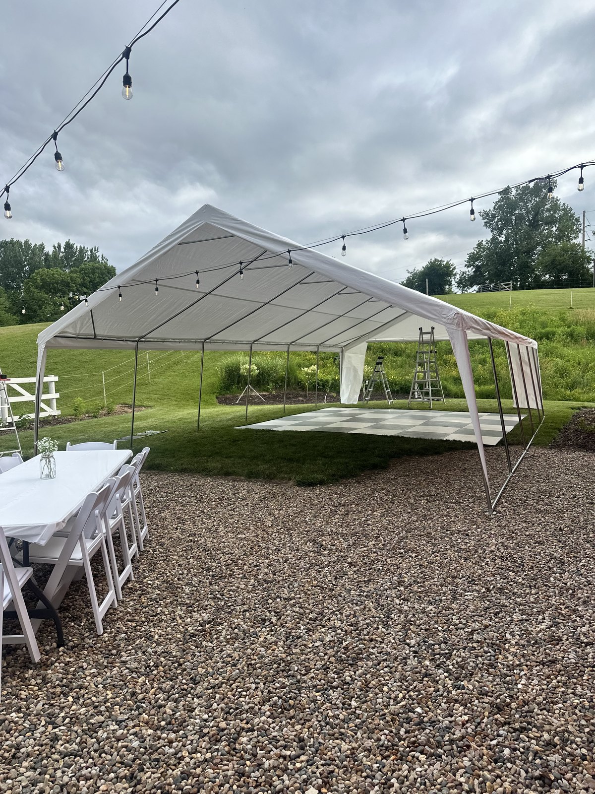 A covered dance floor beneath a reception tent and string lights at Bella's Farmhouse